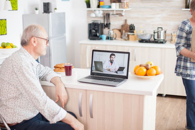 Midsection of man using mobile phone while sitting on table