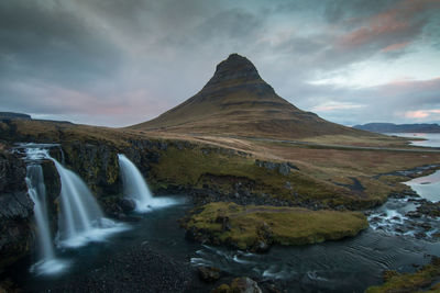 Scenic view of waterfall against cloudy sky