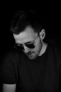 Portrait of young man wearing sunglasses against black background