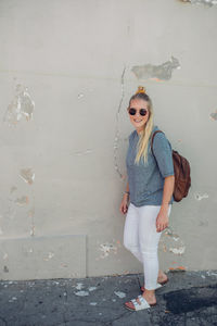 Young woman standing against wall