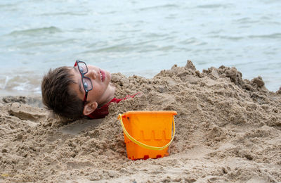 A young boy is buried in the sand on the shores of lake m michigan usa