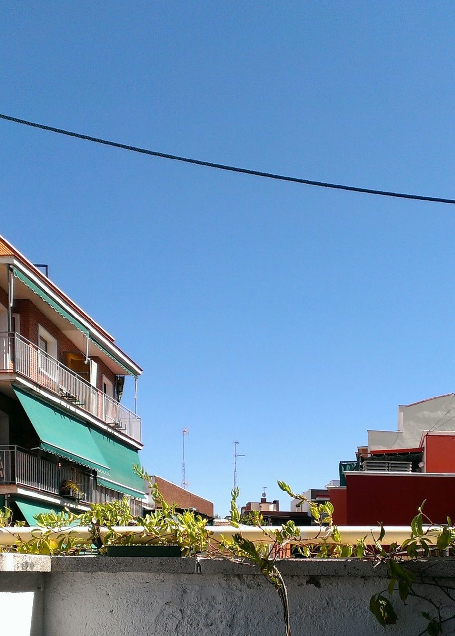 building exterior, architecture, built structure, clear sky, blue, residential structure, house, residential building, copy space, power line, cable, low angle view, day, city, residential district, town, building, outdoors, sunlight, no people