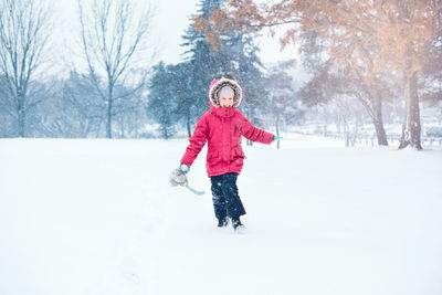 Portrait of cheerful girl running on snow covered land