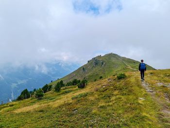 Rear view of man walking on mountain against sky