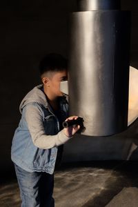 Boy looking through metallic built structure