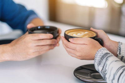 Midsection of man holding coffee cup on table