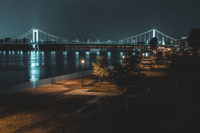 Illuminated bridge over river in city at night