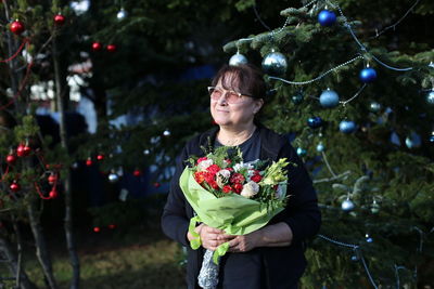 Full length of woman standing against christmas tree 