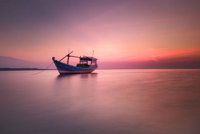 Boat in sea against sky during sunset