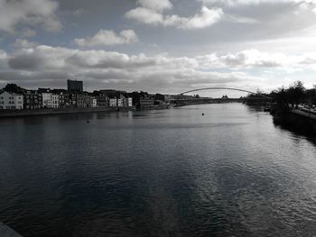 View of city at waterfront against cloudy sky