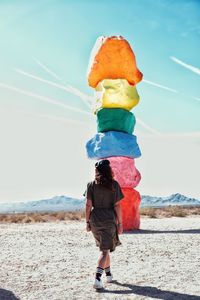 Rear view of woman walking towards colorful rock formations