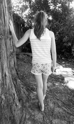 Rear view of young woman standing against trees