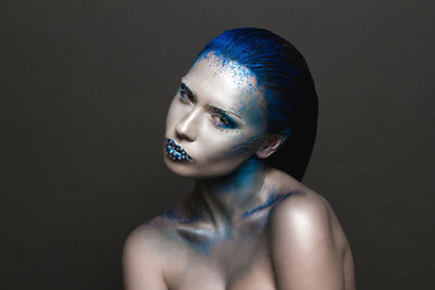 Close-up portrait of woman wearing make-up against black background