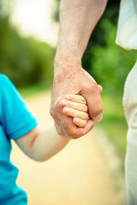 Close-up of man and boy holding hands