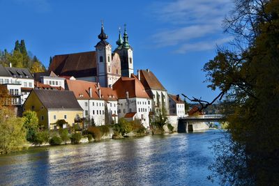 Buildings by river against sky