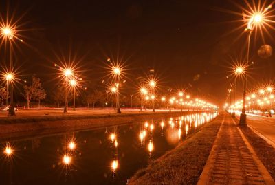 Illuminated street lights by river at night