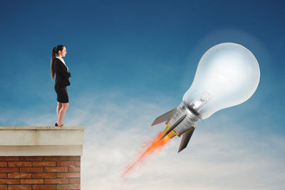 Full length of woman standing against blue sky