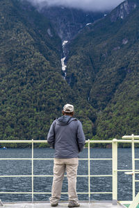 Rear view of man looking at lake against mountain