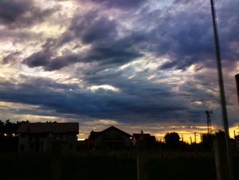 Houses against cloudy sky at sunset