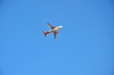 Low angle view of airplane against clear blue sky