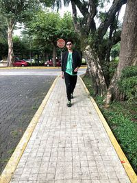 Full length portrait of young man standing on footpath