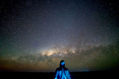 Rear view of man standing against star field at night