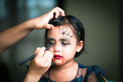 Mother painting daughters face. halloween party.
