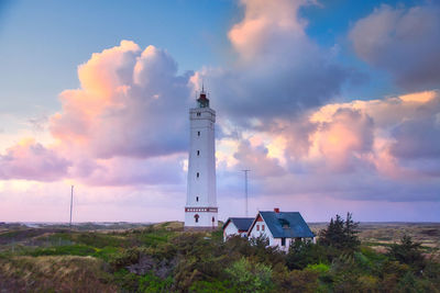 Lighthouse amidst buildings against sky during sunset