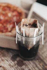 Brewing coffee in a drip bag in a transparent glass, on a wooden background. hot ground drip coffee