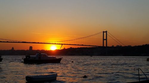 Boats sailing in river against clear sky during sunset