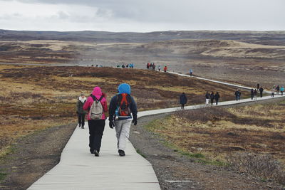 Rear view of people walking on mountain against sky