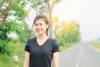 Smiling young woman standing on road