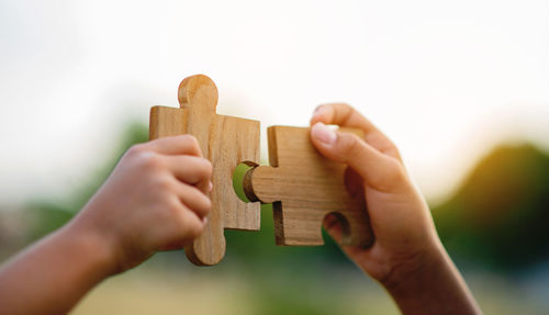 Close-up of hand holding toy blocks against white background