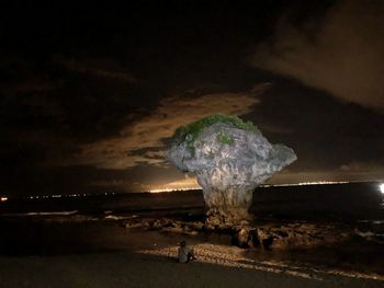 Scenic view of rocks at beach against sky at night