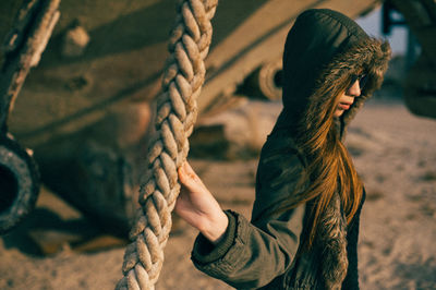 Side view of woman standing by rope at beach