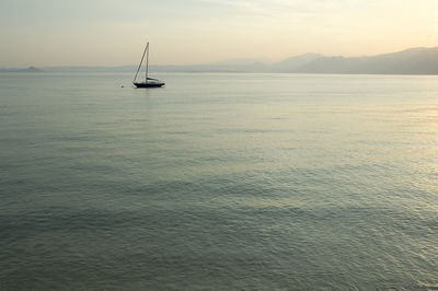 Sailboat sailing on sea against sky during sunset