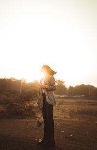Rear view of woman standing against sky during sunset