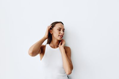 Portrait of young woman standing against white background