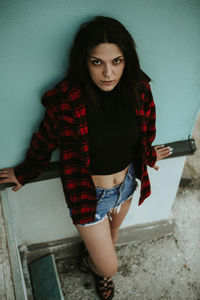 Portrait of young woman standing against wall