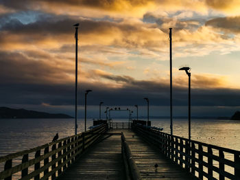 Pier over sea against sky during sunset