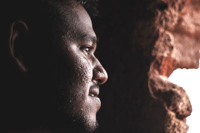 Close-up of young man looking away at cave