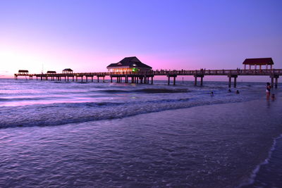 Pier over sea against clear sky at sunset