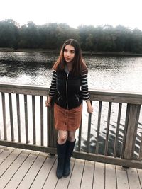 Beautiful woman standing by railing against lake