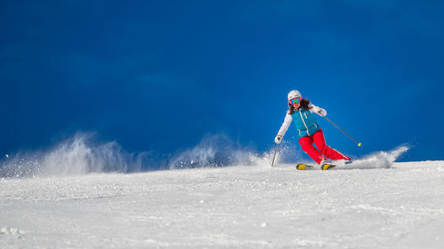 Full length of woman skiing on snow against sky