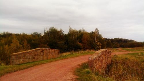 Road amidst field against sky