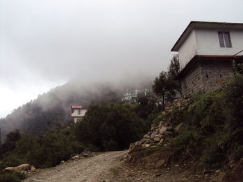 House amidst trees against sky during rainy season