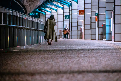 Rear view of two people walking in corridor