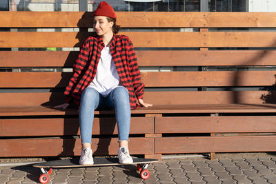 Full length of woman with skateboard sitting outdoors