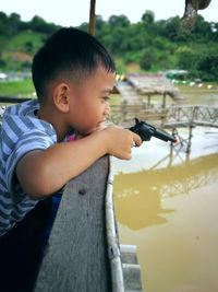 Side view of cute boy looking away while holding toy gun