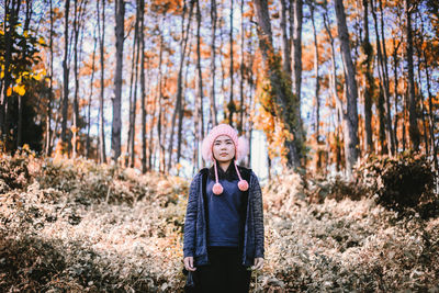 Portrait of smiling woman standing in forest during winter